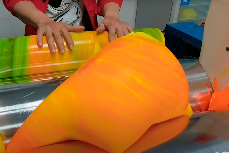 Imagen del proceso de teñido de la silicona para pulseras entre 2 rodillos metálicos.